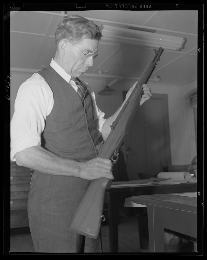 The man behind the gun. John C. Garand, inventor of the semi-automatic rifle now being turned out in large quantities under the war program, looks over one of the guns
