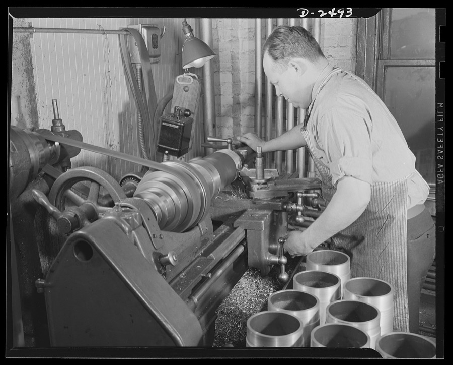 Conversion. Food machinery plant. Cutting of spouts for anti-tanks guns such as those shown in the foreground is the present work of this lathe, formerly used in the production of cube steak machines in a New England plant which is now turning out a number of parts for war machinery on subcontract. Conversion of this machine, and the stepping up of its speed required only a few hours. The operator, Ralph Hutchings, has also turned his skill to war work. He formerly operated a lathe in the production of cube steak machinery. Cube Steak Machine Company, Boston, Massachusetts