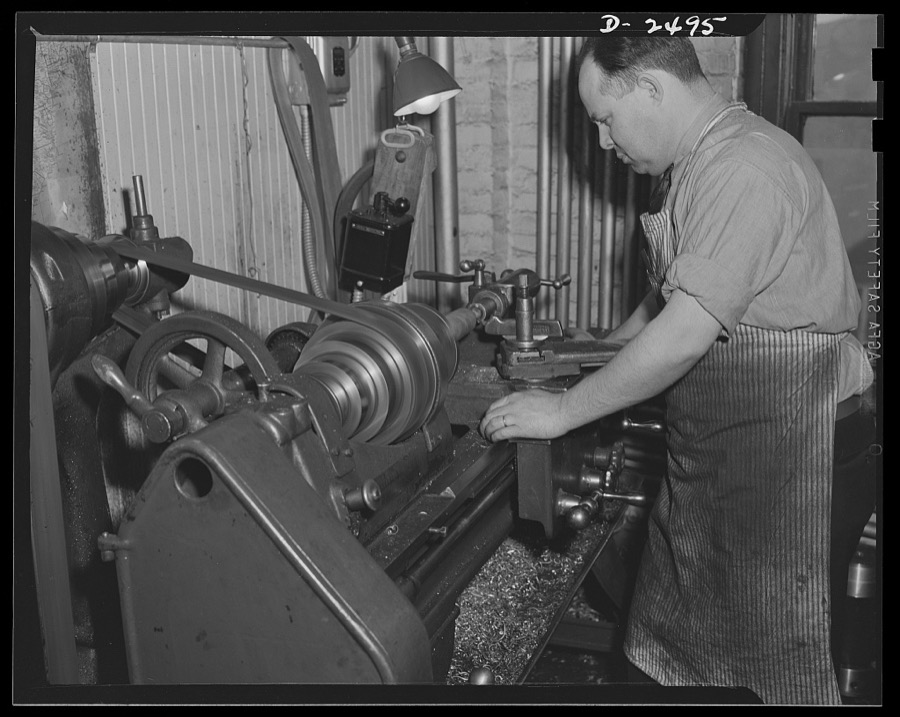 Conversion. Food machinery plant. Cutting of spouts for anti-tank guns is the present work of this lathe, shown here at its former job-shaping wooden rollers used with a belt control to carry steaks into the cube steak machine which is this New England plant's normal production. Conversion of this lathe, and the stepping up of its speed, has turned his skill from peacetime work to war production. Cube Steak Machine Company, Boston, Massachusetts