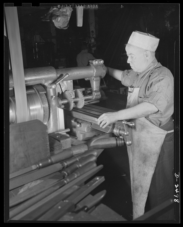 Conversion. Food machinery plant. John J. Morris used to cut steel disc covers with his universal milling machine. These disc covers were part of the cube steak machines which are the normal products of the New England plant where he is employed. Today, however, Morris uses the same machine, tooled over for war subcontract work, for the cutting of large hexagonal nuts for a government arsenal. For cube steak machinery there was only one milling wheel, instead of the two shown above. "Hexing a nut" is a very simple job with a machine designed to shape the nut in a single operation, but such a machine is not available and time is short. Morris, therefore, shifts the round steel stock three times, cutting two sides at a time. Cube Steak Machine Company, Boston, Massachusetts