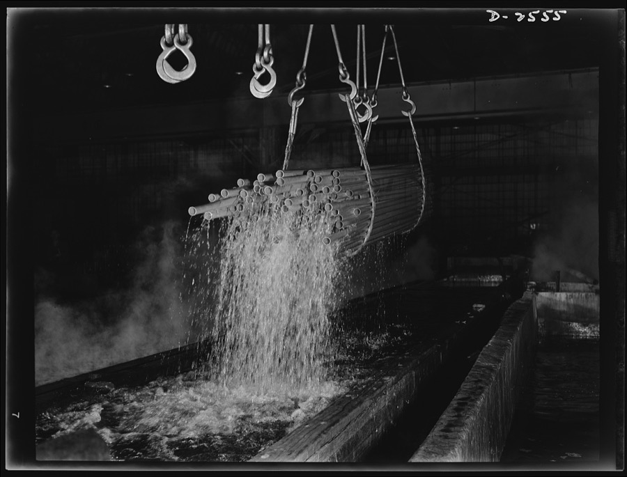 Conversion. Copper and brass processing. Pickling lengths of copper water tube in a brass and copper mill. After annealing, or softening by heat to reduce brittleness and allow further drawing, tubes are "pickled" in a sulphuric acid solution to remove oxide and scale that result from the anneal. Bundles of the tubes are picked up by electric cranes and transported from the pickle to a rinse bath of water. The tubes are then returned to the drawbench for re-drawing down to smaller diameters. Chase Copper and Brass Company, Euclid, Ohio