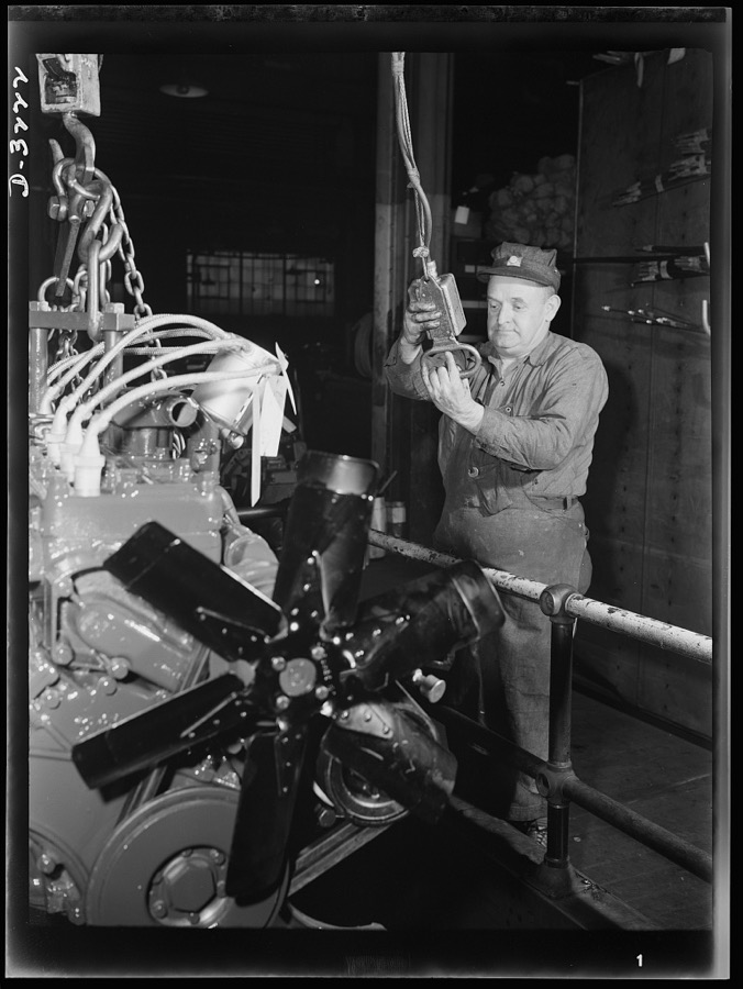 Power for the Army! The engine for an halftrac scout car is raised by electric hoist to the assembly floor of Midwest truck plant. Scout cars in which these engines were and are installed are expected to play a vital role in the war program. White Motor Company, Cleveland, Ohio