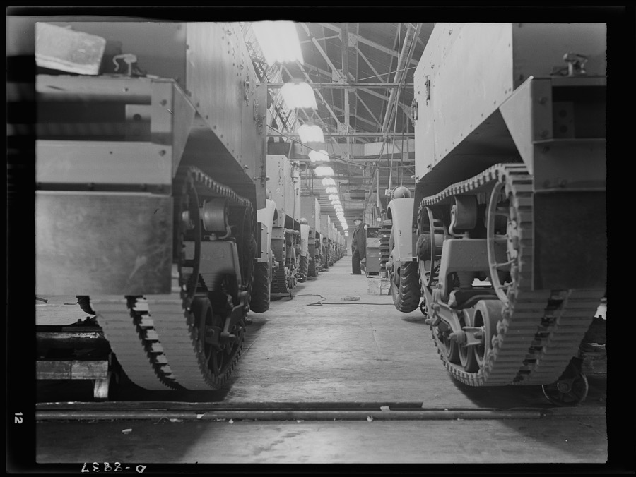 Production. Halftrac armoured cars. Partly finished halftrac scout cars travel along a moving assembly line in a plant converted from the manufacture of safes and locks. The bodies are made in this plant and mounted on chassis produced in a converted automobile plant. Diebold Safe and Lock Company, Canton, Ohio
