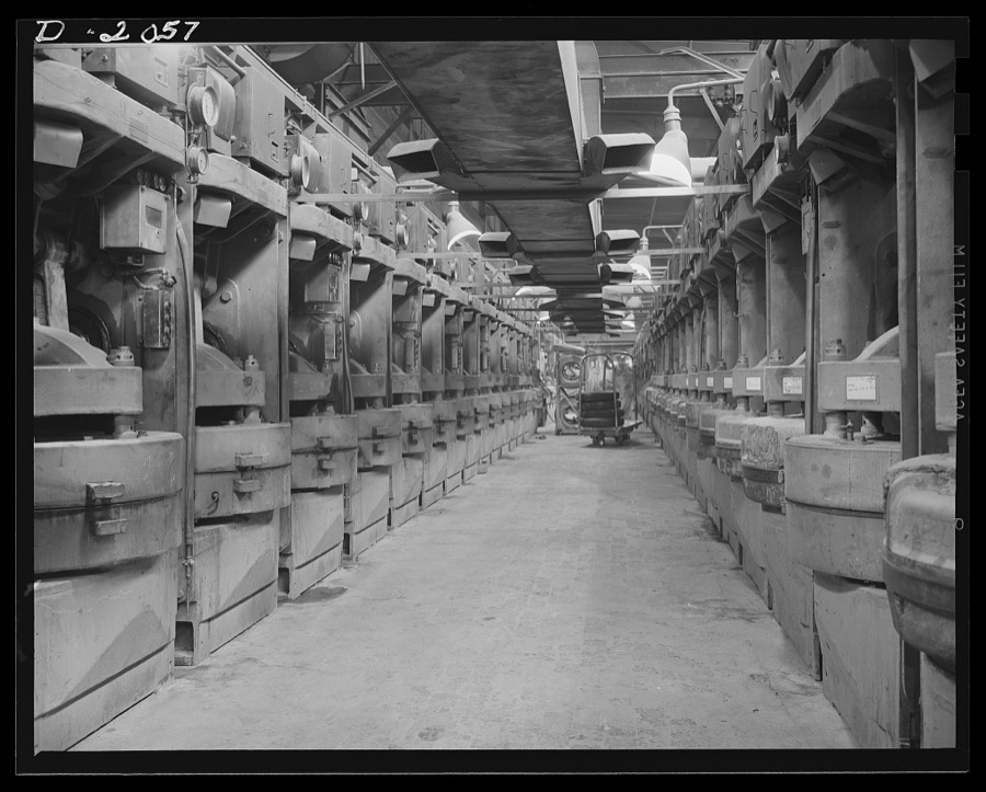 Battery of curing molds. While the curing, or cooking, operation is going on for the tire we have followed through the plant, it is also going on simultaneously for hundreds of other tires in production. This view shows one corridor in the curing room where fifty tires are being cured at once. Additional molds flank this group on both sides of long corridor such as this one. Firestone (General) Tires, Akron, Ohio