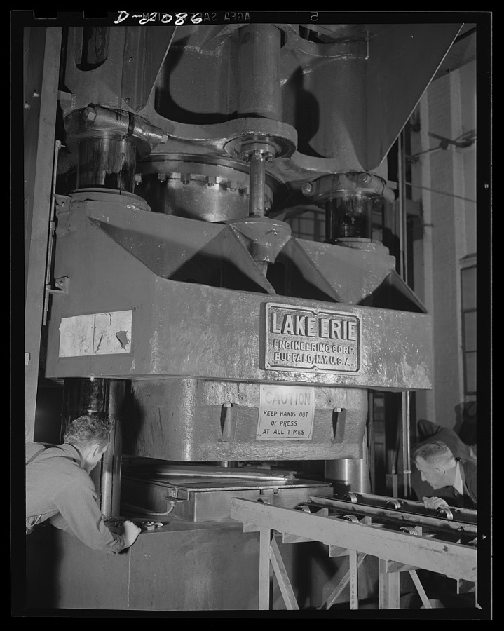 Subcontracting aircraft parts. This giant hydraulic press with rubber insert is used to stamp out numerous sub-assembly parts for planes at this huge converted airship dock. These "sub-assembly" parts are put together at the different plants and then sent to the plane plants for inclusion in the finished plane. Goodyear, Akron, Ohio