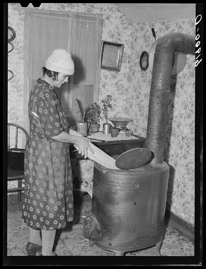 Wife of day laborer putting wood in stove. Scioto Marshes, Hardin County, Ohio